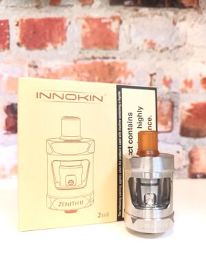 Innokin Zenith II tank and box displayed on a white shelf in front of a brick background