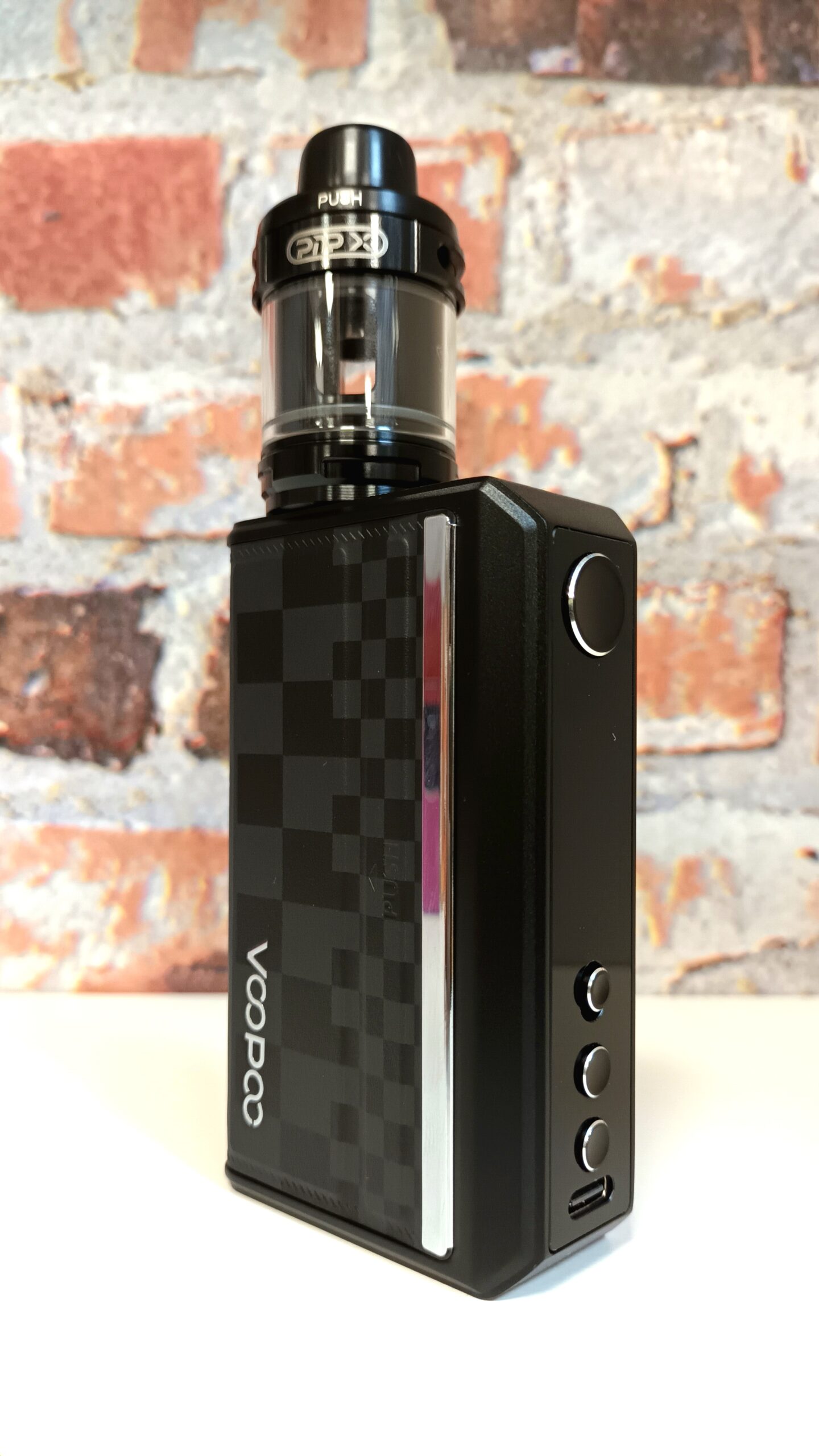 Voopoo Drag 5 on white shelf in front of brick background